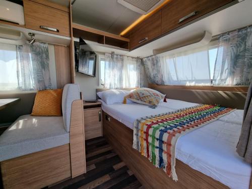Habitación pequeña con cama y sofá. en Glamping Caravans In The Crater- גלמפינג קרוואנים במכתש רמון en Mitzpe Ramon