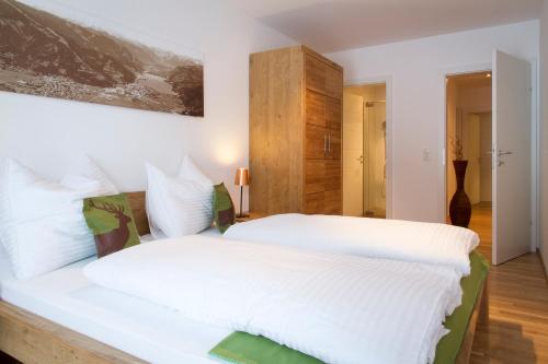 een slaapkamer met een groot bed met witte lakens bij Steinbock Superior Appartement in Zell am See