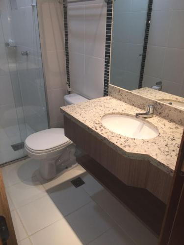 a bathroom with a sink and a toilet and a mirror at Veredas do Rio Quente - Flat 726 - Fantástico!!! in Rio Quente