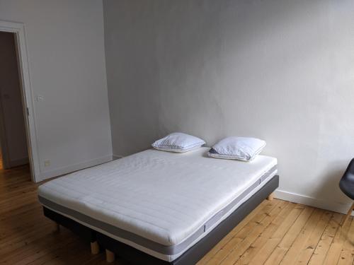 a bed with two pillows on it in a room at Logis de la Grande Rue, appt cœur de ville, spacieux, lumineux, parquet 3 chbres, - 6 pers in La Flèche