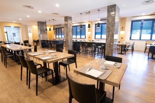 a restaurant with wooden tables and chairs and windows at Piccolo Hotel in Ravenna