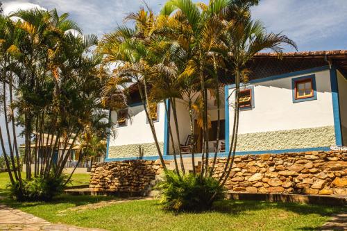 a house with palm trees and a stone wall at Pousada Canto Verde in Serra do Cipo