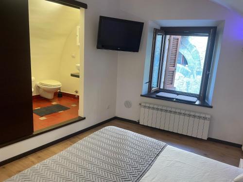 a bathroom with a toilet and a television on the wall at Il Nido Etrusco in Orvieto