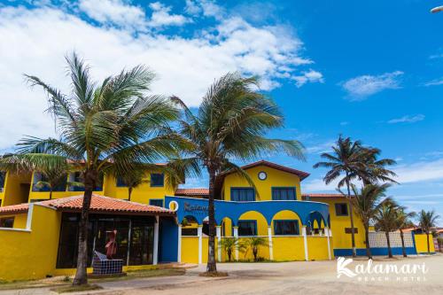 a yellow house with palm trees in front of it at Kalamari Beach Hotel in Aquiraz