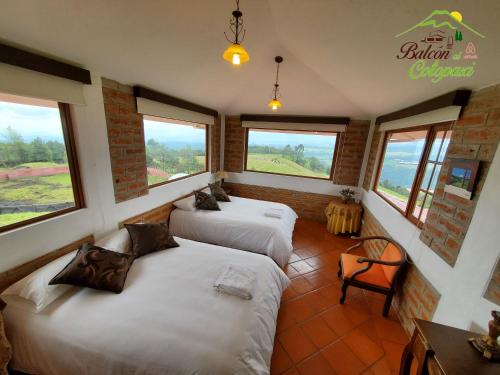 two beds in a room with windows at Balcon al Cotopaxi Hosteria in Sangolquí