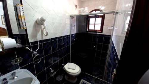 y baño con aseo, lavabo y ducha. en Hotel Shallon, en Campos do Jordão