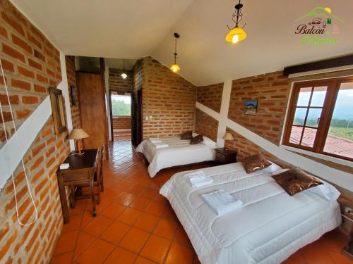 a bedroom with two beds and a brick wall at Balcon al Cotopaxi Hosteria in Sangolquí