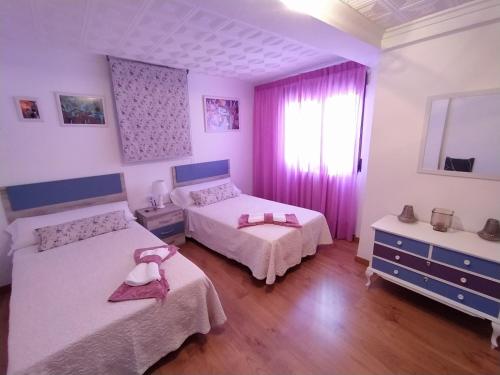 um quarto com 2 camas e uma janela com cortinas cor-de-rosa em Juderia em Teruel
