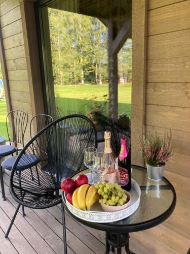 a plate of fruit and wine on a table on a porch at Saules namiņš in Cēsis