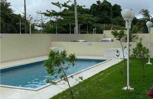 a swimming pool with chairs next to a fence at APTO FAMILIAR EM BERTIOGA JARDINS DO INDAIÁ A 500 M Praia in Bertioga