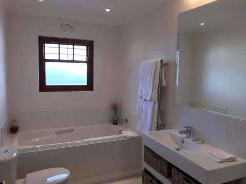 a white bathroom with a tub and a sink at Park West Self-catering in Cape Town