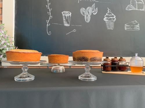 a table with three cakes on plates on a table at Hotel St. Daniel in Guarulhos