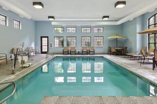 una piscina con mesas y sillas en un edificio en Staybridge Suites Kalamazoo, an IHG Hotel, en Kalamazoo
