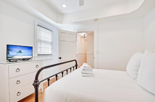 a white bedroom with a bed and a television at Guesthouse Charleston SOUTH 105 A in Charleston