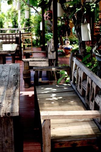 a group of wooden benches sitting on a patio at Asia Hotels Group (Poonpetch Chiangmai) in Chiang Mai