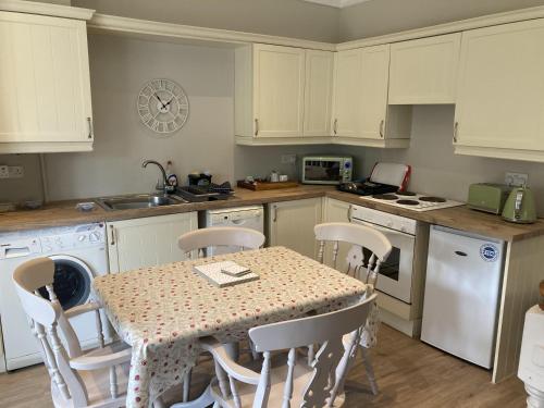 a kitchen with a table and chairs and a kitchen with white cabinets at Pinewood Cottage Deluxe Self Catering Apartments in Lyndhurst