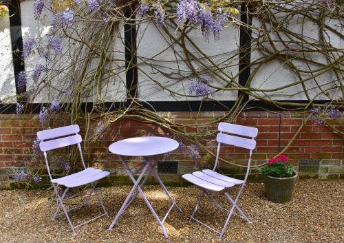 three chairs and a table in front of a brick wall at Pinewood Cottage Deluxe Self Catering Apartments in Lyndhurst