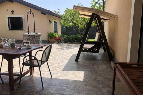 a patio with a wooden table and chairs and a table and a ladder at Casa di Paco a Nicolosi in Mascalucia