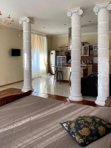 uma sala de estar com colunas brancas e uma cozinha em Просторная солнечная студия с круглым балконом em Vyborg