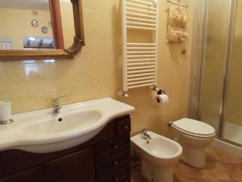 uma casa de banho com um lavatório, um WC e um espelho. em La bouganville em Passoscuro