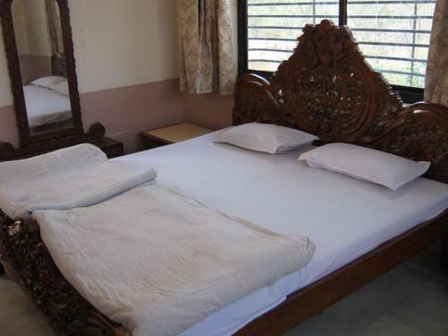 a bedroom with a large bed with white sheets and a mirror at Nav Ratan Palace in Pushkar