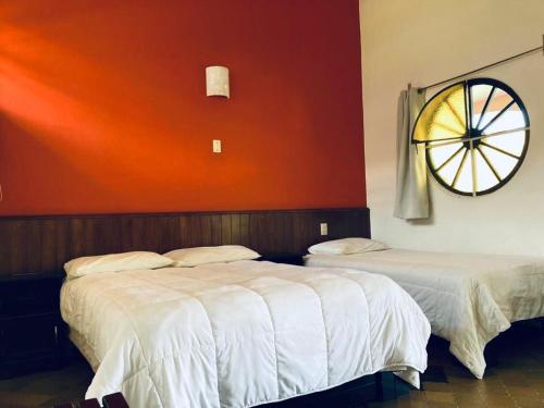 two beds in a room with an orange wall at Hotel Ojo de Agua in Ciudad Hidalgo