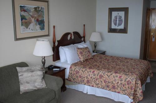 a hotel room with a bed and a chair at Admiral Digby Inn Restaurant and Cottages in Digby