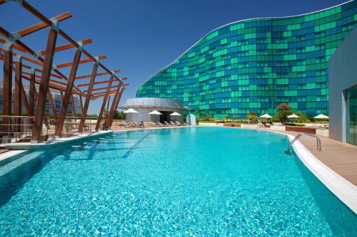 a large swimming pool in front of a building at Millennium Al Rawdah Hotel in Abu Dhabi