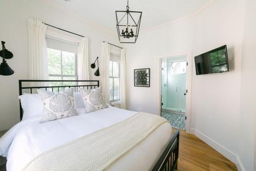Un dormitorio con una cama blanca con almohadas y un televisor. en Guesthouse Charleston WEST 242 C, en Charleston