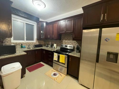 una cucina con mobili in legno e un frigorifero in acciaio inossidabile di Jamrock Suites a Kingston