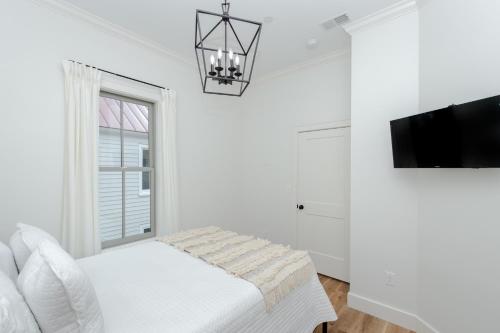 Un dormitorio blanco con una cama y un televisor. en Guesthouse Charleston WEST 242 B, en Charleston