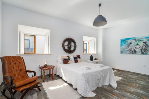 um quarto branco com uma cama e uma cadeira em Casa Celeiro em Estômbar