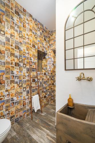 a bathroom with a mosaic tile wall and a tub at Casa Celeiro in Estômbar