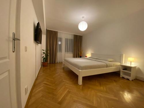 une chambre avec un lit blanc et un parquet dans l'établissement Daniela's Apartaments, à Sighişoara