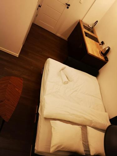 a small bedroom with a bed with white sheets and a dresser at Apartamenty LENA 1 in Racibórz