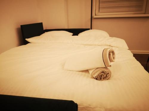 Una cama blanca con una toalla enrollada. en Apartamenty LENA 1, en Racibórz