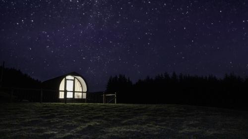 a lit up greenhouse in a field at night at Forester's Retreat Glamping - Cambrian View- Vaccinated dogs over the age of 2 are accepted in Aberystwyth