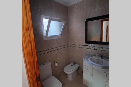 a bathroom with a toilet and a sink and a mirror at Agradable casa para disfrutar con los tuyos in Gran Alacant
