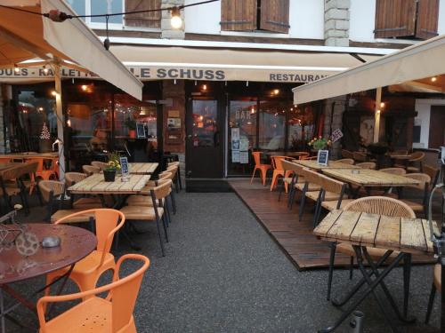 ein Restaurant mit Holztischen und -stühlen davor in der Unterkunft Coquet et accueillant Studio montagne la Mongie in Bagnères-de-Bigorre