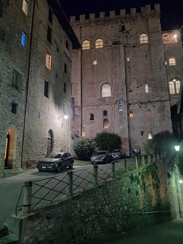 two cars parked in front of a castle at night at Appartamento Gattapone 9 in Gubbio
