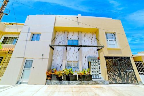 a white house with flowers in front of it at Árbol Suites in Tijuana
