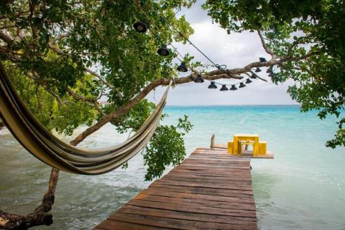 a hammock hanging from a wooden bridge over the ocean at San Fernando, Bacalar Villa Nina Del Río in Bacalar