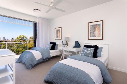 a bedroom with two beds and a desk and a window at The Beach Houses Holiday Villas in Gold Coast