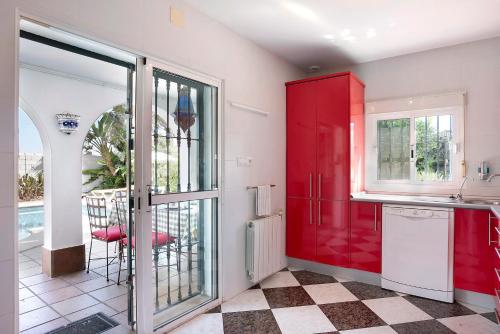 Il comprend une cuisine équipée de placards rouges et d'un réfrigérateur rouge. dans l'établissement Villa Val de Rosa, à Chiclana de la Frontera
