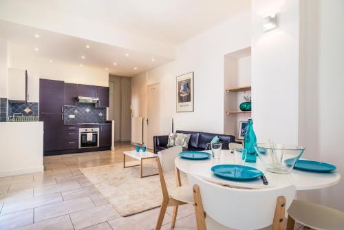 une cuisine et un salon avec une table et des chaises blanches dans l'établissement Modern 2-bedroom City Center Apartment, à Nice