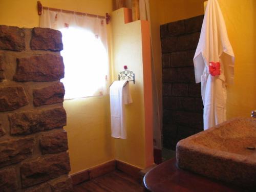 a bathroom with a stone wall and a window at Le Zahir Lodge in Ambatoloaka
