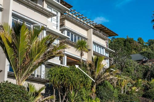 a large building with palm trees in front of it at The Sands - Apartment 19 - Stay Waiheke in Onetangi