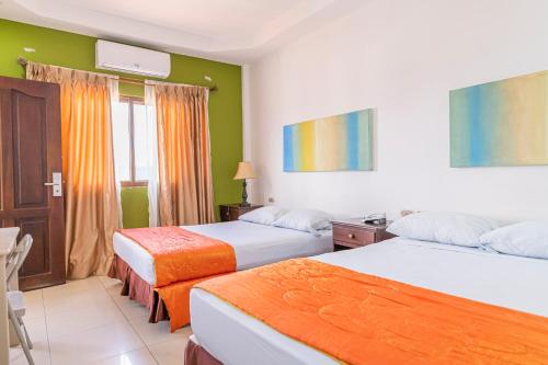 2 Betten in einem Hotelzimmer mit grünen Wänden in der Unterkunft Hotel Santa Fe in Santa Rosa de Copán