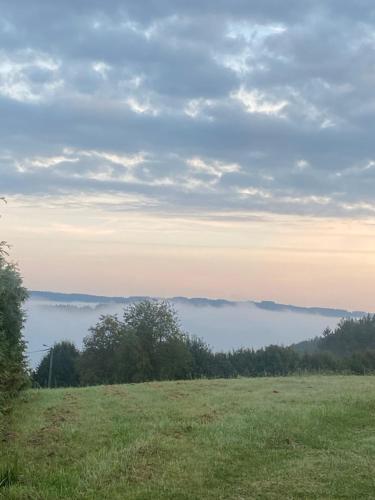 a field with a view of the fog in the distance at Aux 4 chalets in Bouillon