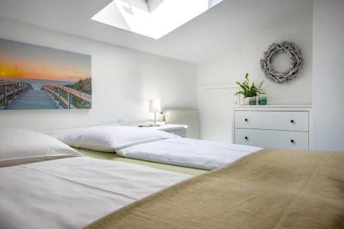 a white bedroom with two beds and a painting on the wall at Knusthof - Wohnung 1 in Albertsdorf